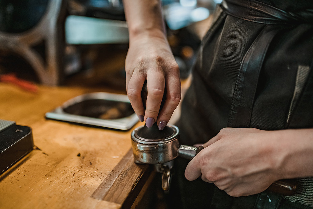 Persona apisonando café molido en un portafiltro con un tamper